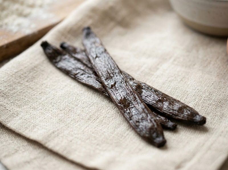 Gousses de vanille tahitensis sur tissu de lin, texture sombre et souple caractéristique de la vanille de Tahiti